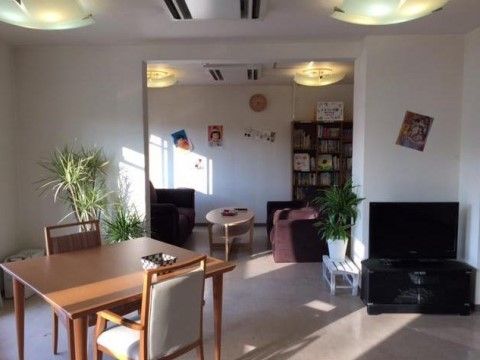 日射しが差し込んでいる明るい空間である。ダイニングテーブルや大型液晶テレビ、書棚が完備されている。食後もくつろげる。
