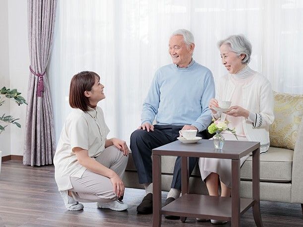 ２人掛けのソファーに斜めに座って厚い本を開いている白髪の男性