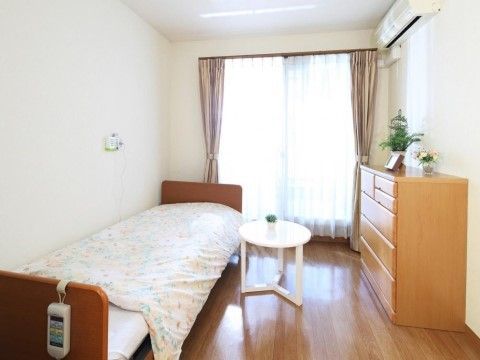 天井や壁が白で統一されている部屋。床やタンスが茶色で、その中にあって、タンスの上の植物の緑が部屋のアクセントになっている。