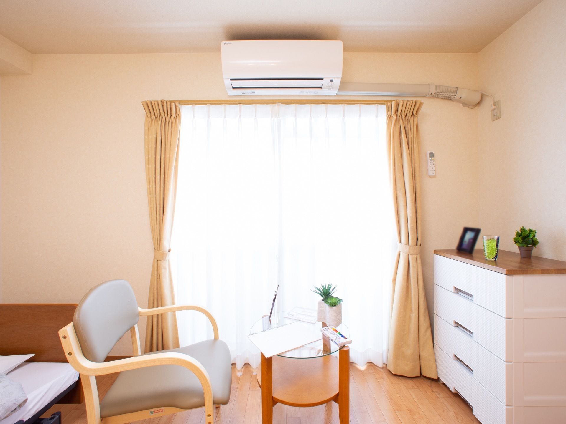 肘掛椅子と電動ベッドが備えられた、ナチュラルな居室