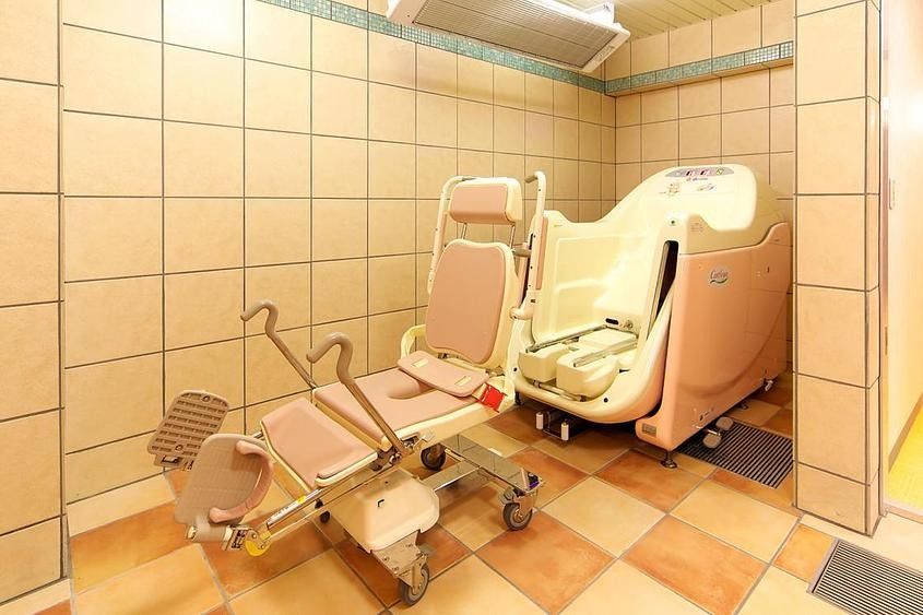 手すりが取り付けられた木製の浴槽が設置された個浴用浴室