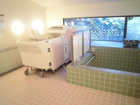 床がピンク色のタイル張りの浴室である。そこには緑色のタイル張りの大きめの浴槽があり、横に機械浴槽も置かれている。
