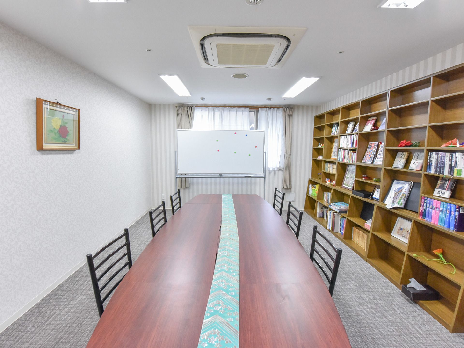 窓を背にしてホワイトボードが立っている。また単なる事務的な空間にならないよう、壁には絵画が飾られている。
