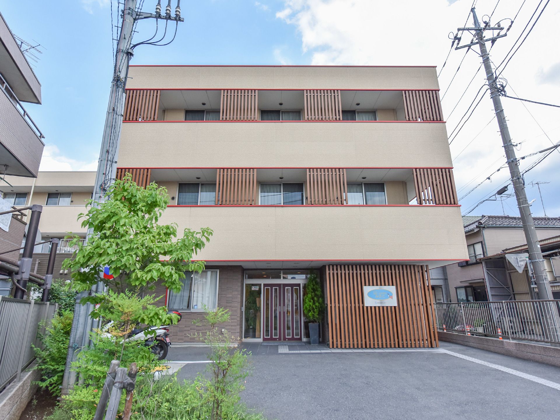 格子状の壁が所々に配置されている３階建ての施設外観