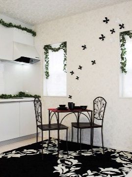 キッチン横に置かれたダイニングテーブル。真っ白い空間に、緑の葉や黒や白で作られた装飾が鮮やかに映える。