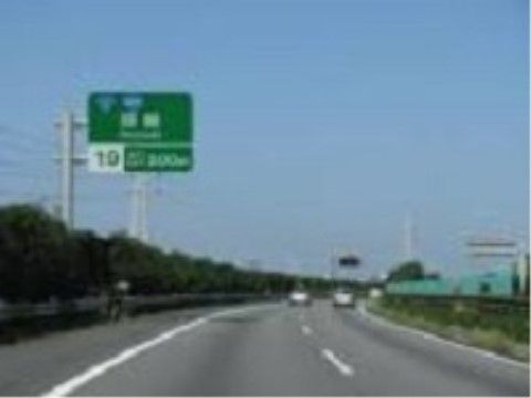 施設の近くにある片側２車線の高速道路の様子。路肩の柵の向こうには木々が植えられ、車が走って行くのが分かる。