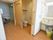 個室に入って左側には手すり付きのトイレがある。鏡付きの洗面台もあり、収納棚がある。ごみ箱も置いている。