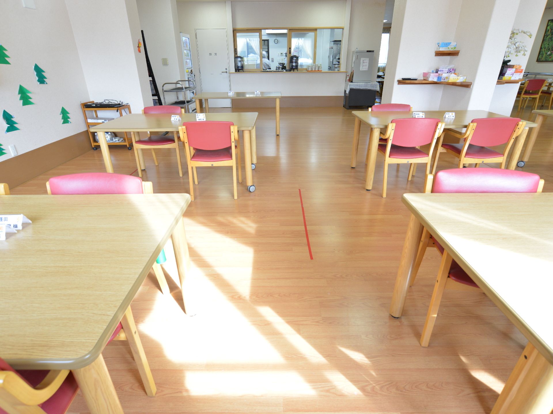 食堂となっている部屋にはナチュラルな色の木製のテーブルとピンク色の椅子が並べられている。カウンターテーブルにはコップが置かれている。