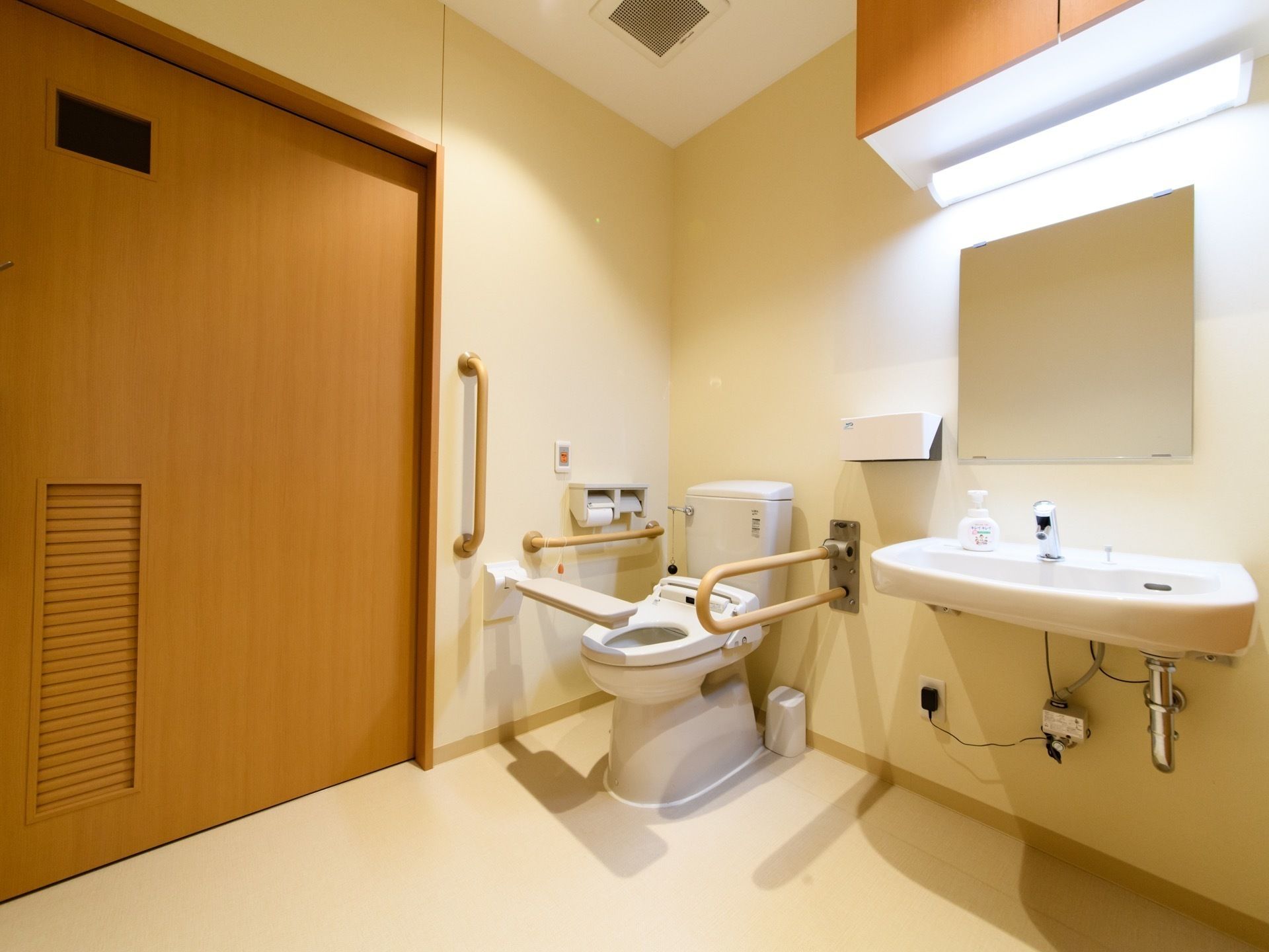 共有のトイレは車椅子をご利用の方も使いやすい広々した作りになっている。可動タイプの肘掛けが付けられ、リラックスして利用できる。
