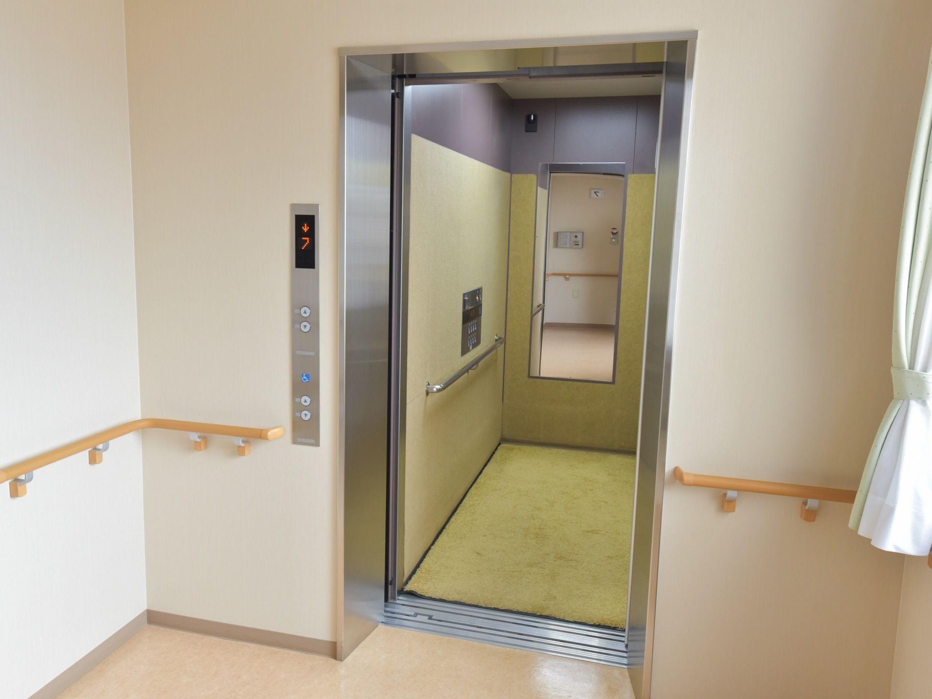 エレベーター入口付近の壁ギリギリと中には手すりが設置されている。縦長の鏡も取り付けられている。操作ボタンもある。