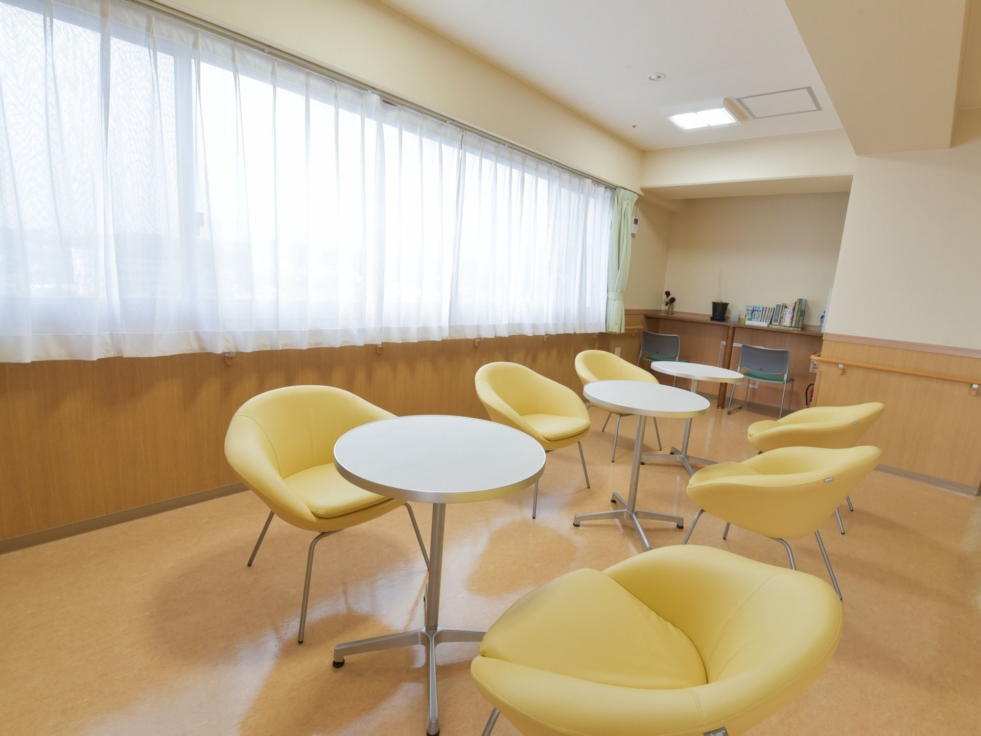 円卓テーブルの周りに迎え合わせに背もたれ付きの椅子が並べられている。部屋の端には座って本を読めるスペースもある。