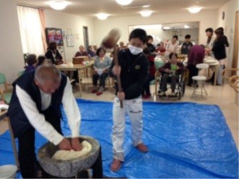 臼と杵を使った餅つきが行われており、それを見学する人たち