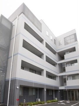 駐車場があり、スタイリッシュなグレーの外壁の五階建ての建物