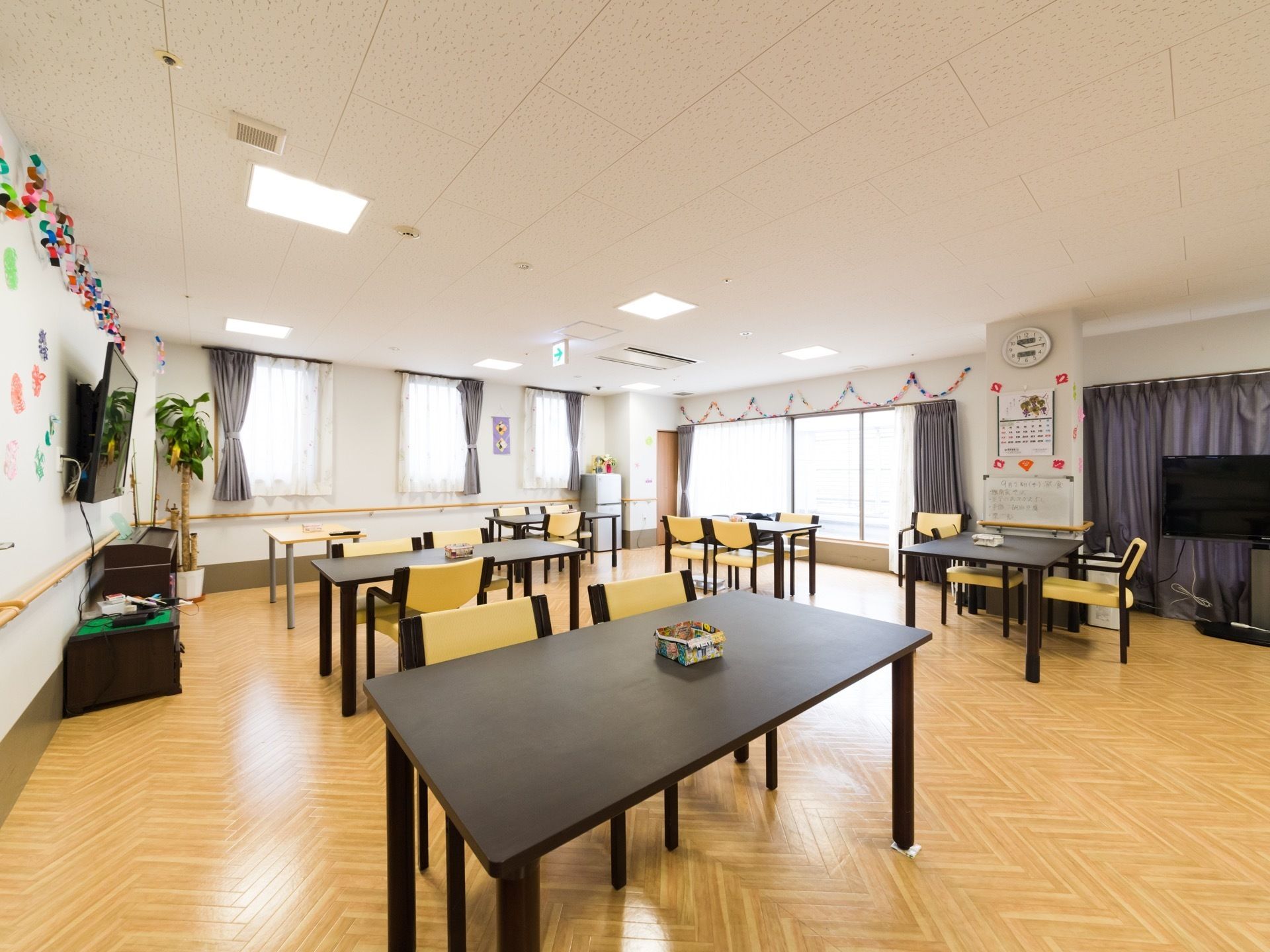 2方向に窓がある広い空間の食堂は、日当たりが良くとても明るい。壁には手すりが取り付けられているので、安全面にも配慮している。