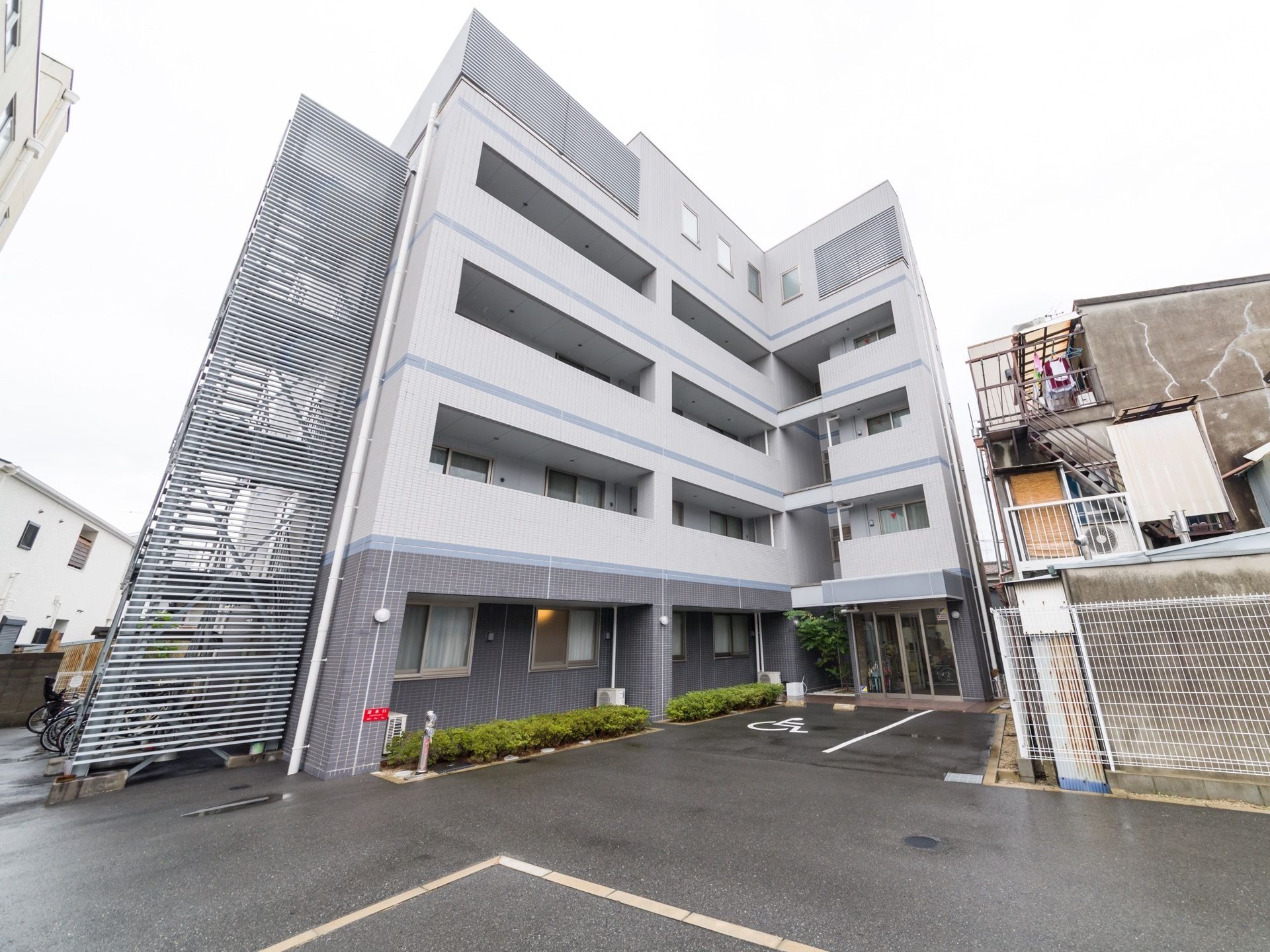 5階建て薄いグレーの施設で非常用階段が左側に設置されている。玄関はフラットなバリアフリーの造りになっているので、出入りがスムーズである。
