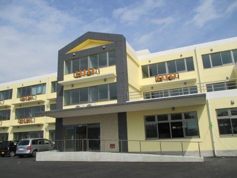 クリーム色の外壁が特徴的なデザインになっている三階建ての建物