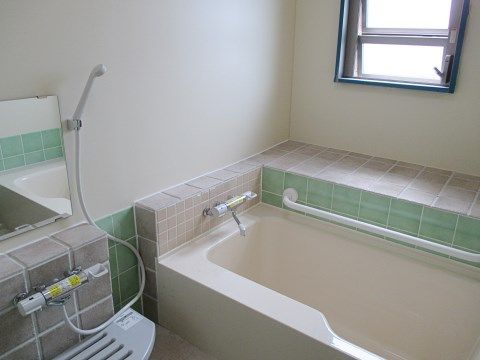 シャワーが取り付けられた落ち着いた色合いの浴室。浴槽わきに手すりがついているため、安全に出入りできる。