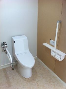 温水洗浄便座が設置されているトイレ。２か所に手すりを取り付けてある。自動で便座ふたが開閉するため、清潔に利用できる。