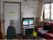 家庭のような雰囲気のリビング。入居者様がソファに座りながらテレビ鑑賞をしている。テーブルに花が飾られている。