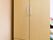 縦長のベージュの洋服ダンスがある。上部は金属の取っ手がある観音開きの収納になっており、下部に２段引き出しがある。