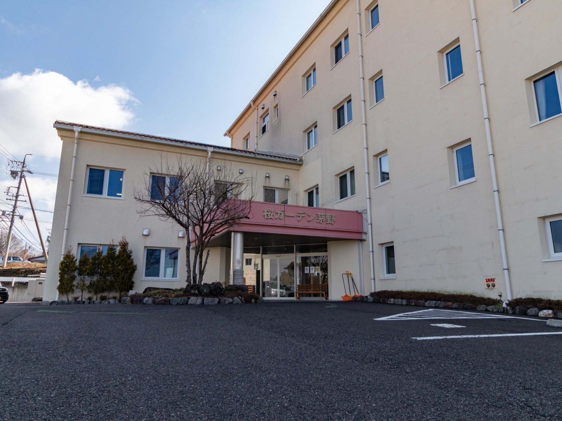 施設は外壁がベージュ色の４階建ての建物である。玄関前にはえんじ色の屋根がついており、施設名が表示されている。
