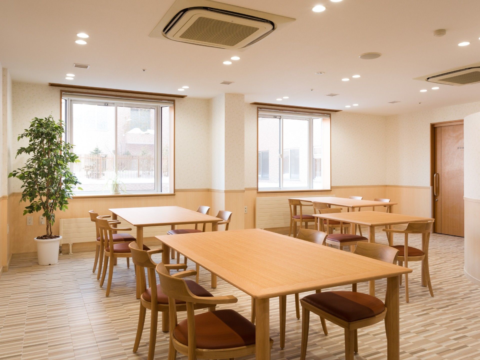 居間には、4人がけのテーブルと椅子が置かれている。2つある窓からは、太陽の光が差し込み、明るい空間となっている。