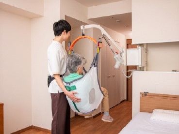 部屋に設置してあるリフトに乗って室内を移動している女性