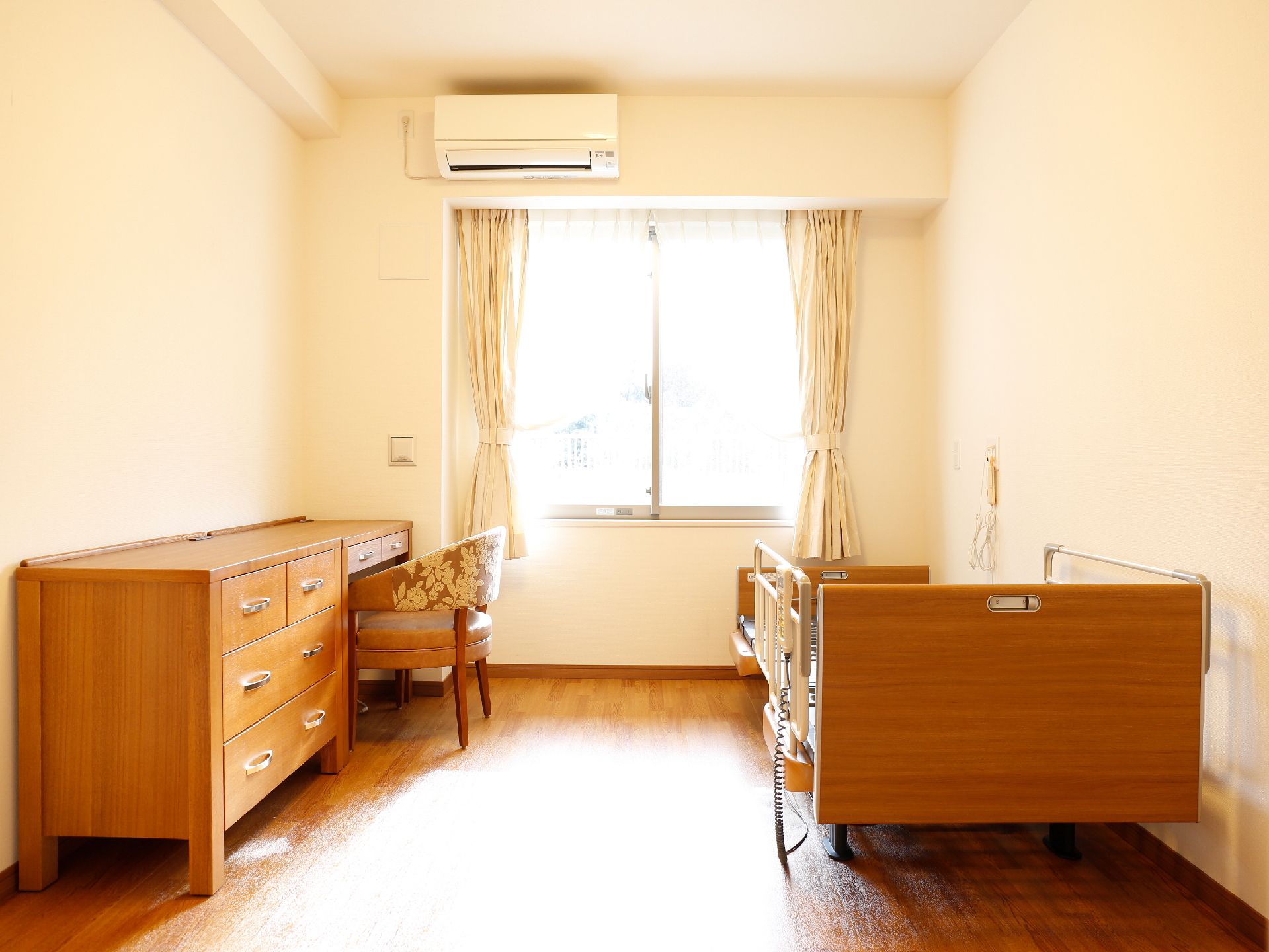 介護用のベッドと、温かみのある木調の家具が置かれた部屋