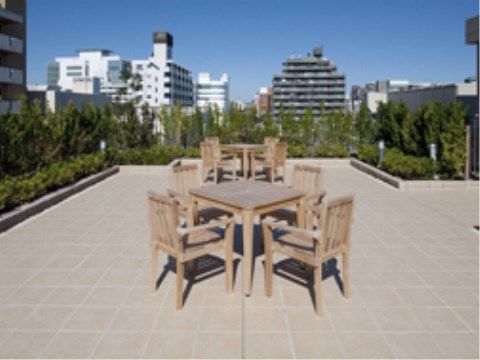 テーブルと椅子が置かれている、植栽と花壇のある屋上庭園