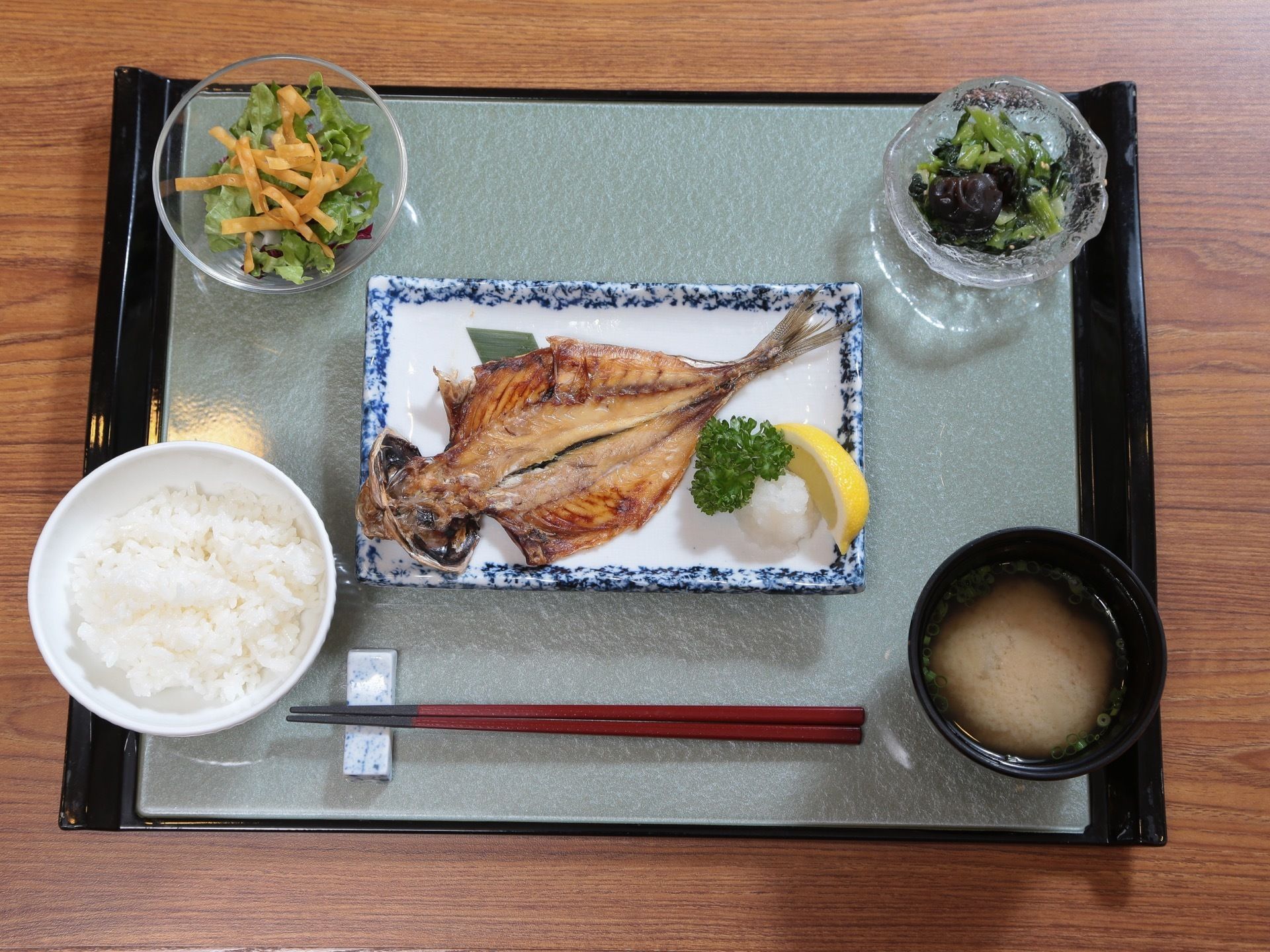 焼き魚メインに小鉢２つ、ご飯と汁物の食事である。魚には、大根おろしとパセリ、レモンなどを添え、美味しくいただける工夫もある。