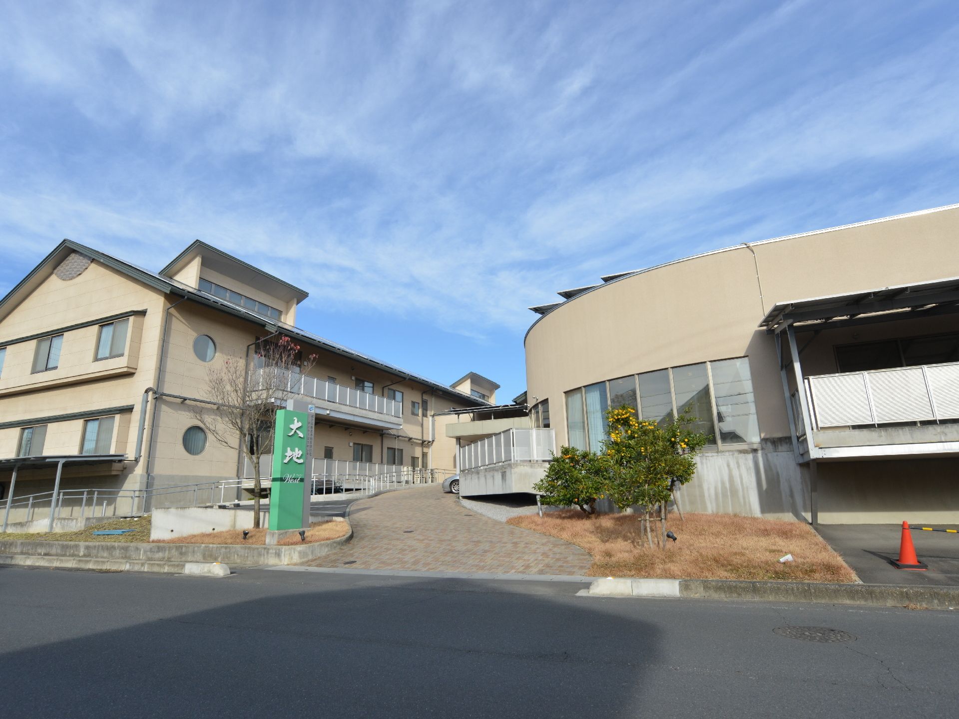 施設は2階建ての個性的なデザインの建物。道路から入り口のアプローチはバリアフリー仕様の緩やかな坂になっている。