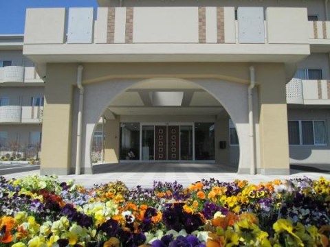 色とりどりの花が植えられた向こうにある建物のエントランス