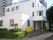 白を基調とした3階建ての建物は角ばったデザインで玄関の前には屋根があり、周辺には緑がたくさん植えられている。