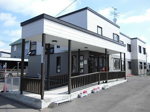 モノトーンの2階建ての建物は日当たりのいい場所にあり、玄関には手すり付きのスロープが付いている。