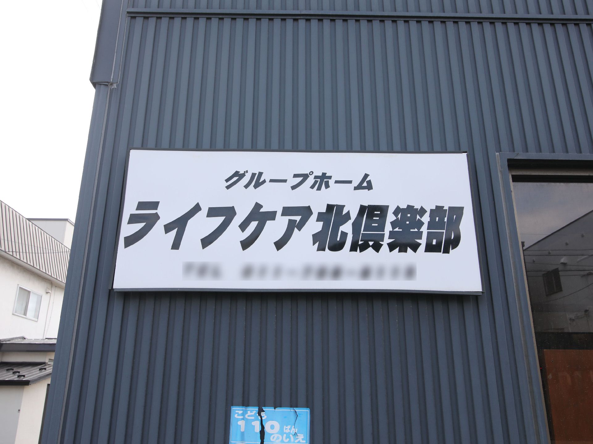 黒い壁についている建物の名前が入った白いプレート
