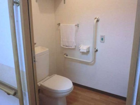 バリアフリー対応の、手すりが付いた広々としたトイレである。毎日、なるべくトイレで排泄していただけるようにサポートを行っている。