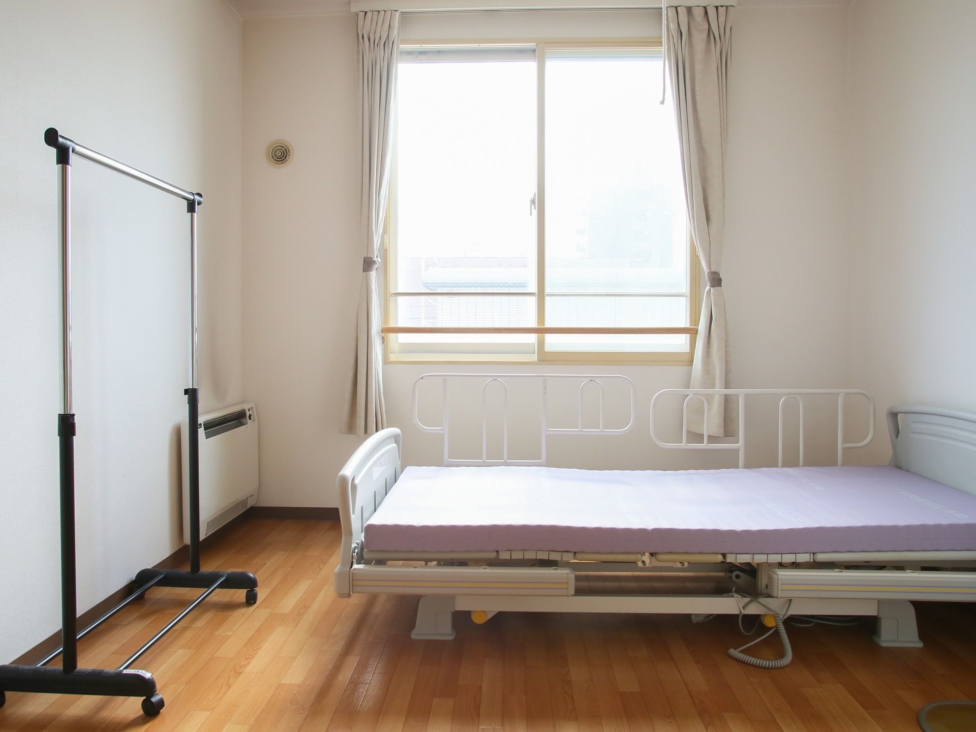 居室奥にはベッドが設置されており、片面には転落防止用の柵が取りつけられている。最奥の壁には窓があり、明るい自然光を室内に注いでいる。