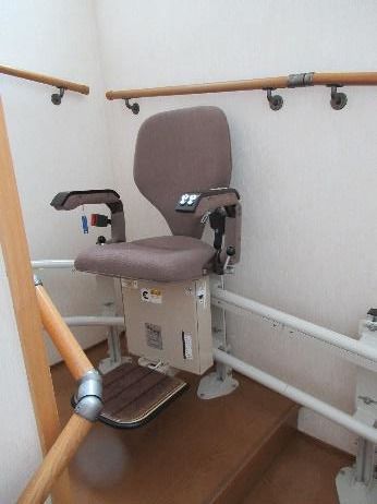 手すりが付いた階段には昇降機が設置されている。昇降機には肘置きもあり、フットレストもある。