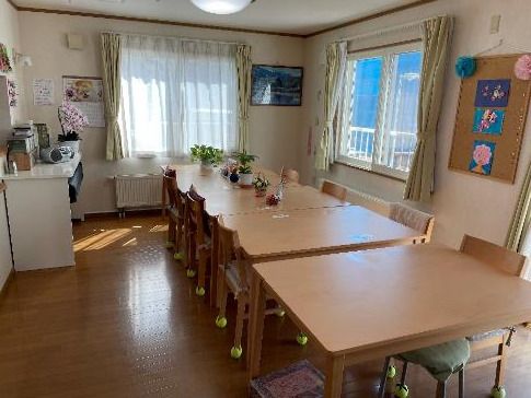 花や絵が飾られた食堂の中央に木製のダイニングテーブルが置かれ、テーブルには調味料や花もある。