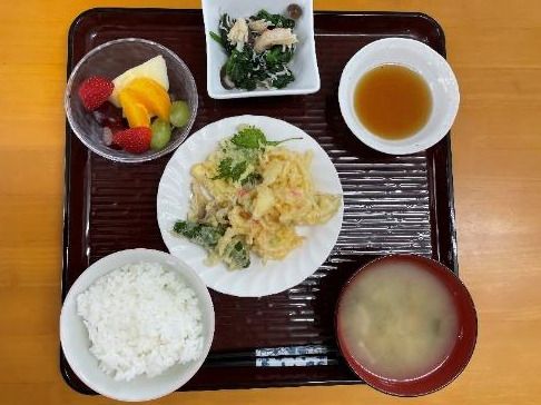 揚げたての天ぷらが中央に置かれ、白いご飯やみそ汁、天つゆ、カットフルーツの盛り合わせが並んでいる。