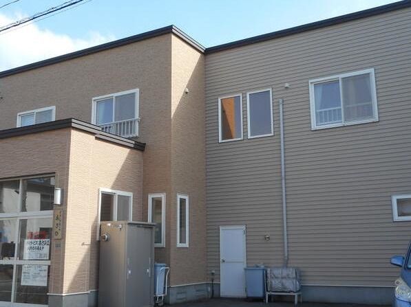 ２階建ての建物は2階ブラウン系で、日当たりのいい場所に建っている。玄関には張り紙が貼られている。