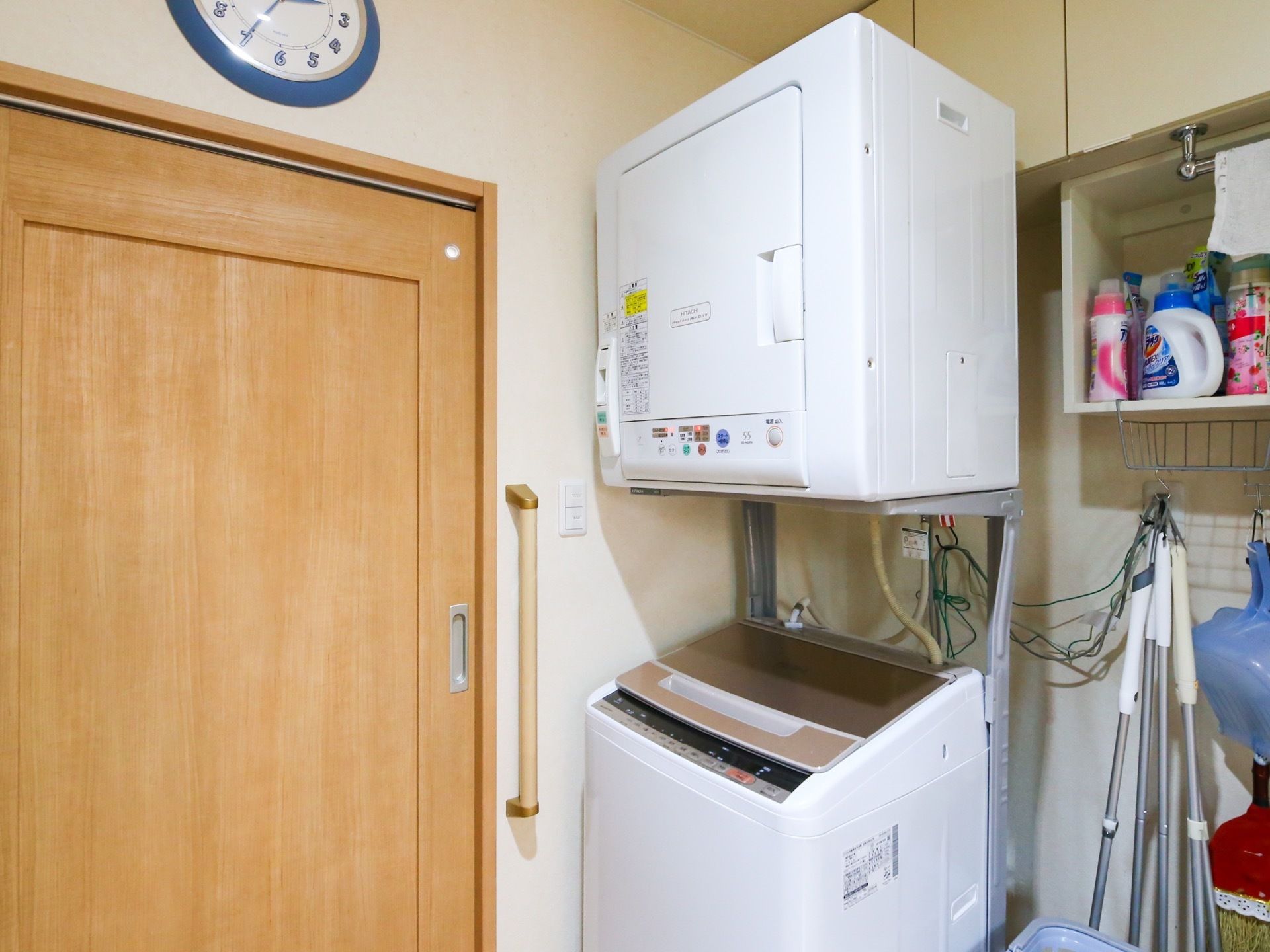 洗濯機の上には、乾燥機が用意されている。横には掃除道具がかけられており、上部には多数の洗剤が置いてある。