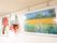 壁に大きな絵画が飾られており、その間には花束が展示されている。絵画は、花の入った花瓶と花畑の絵である。
