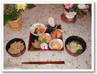 和食のセットと、赤やピンクの花が飾られた食卓