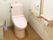 ピンクのトイレはエル字型の手すりが付き、横にはゴミ箱もある。