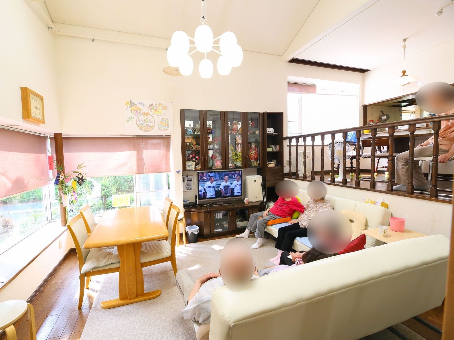 Ｌ字型のソファーに座りテレビを鑑賞してくつろぐ高齢者