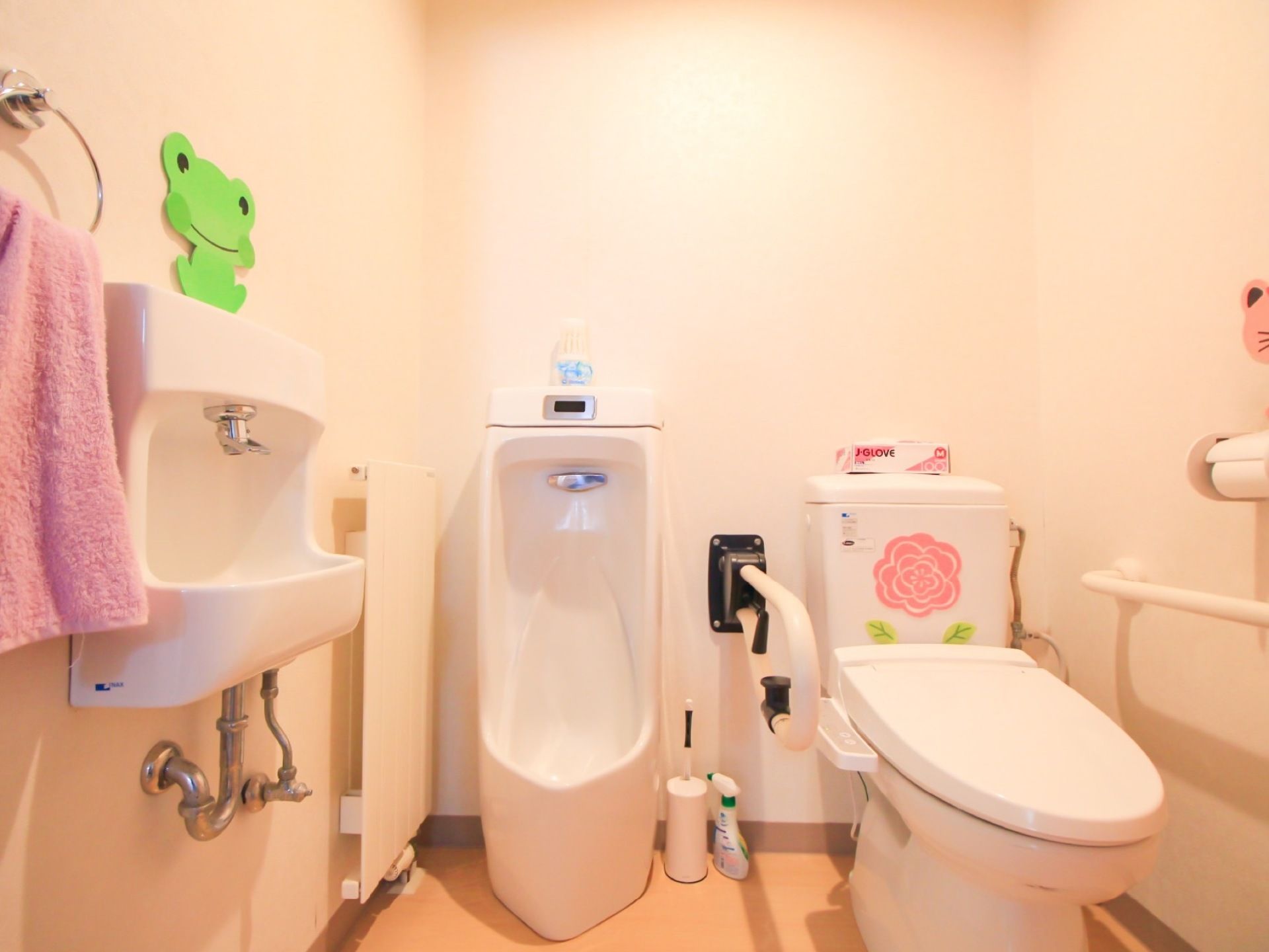 暖房が完備されている共用トイレ。手洗い場の上の壁にはカエル、便器には花をモチーフにした飾りが施されている。