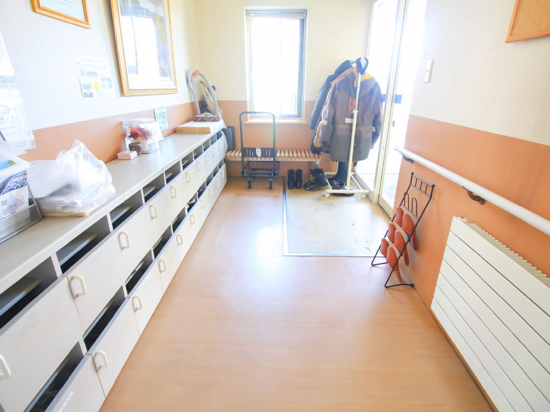 入居者様一人ひとり専用の靴箱が用意されており、扉で閉められるようになっている。自動ドア横のラックには、スリッパが用意されている。