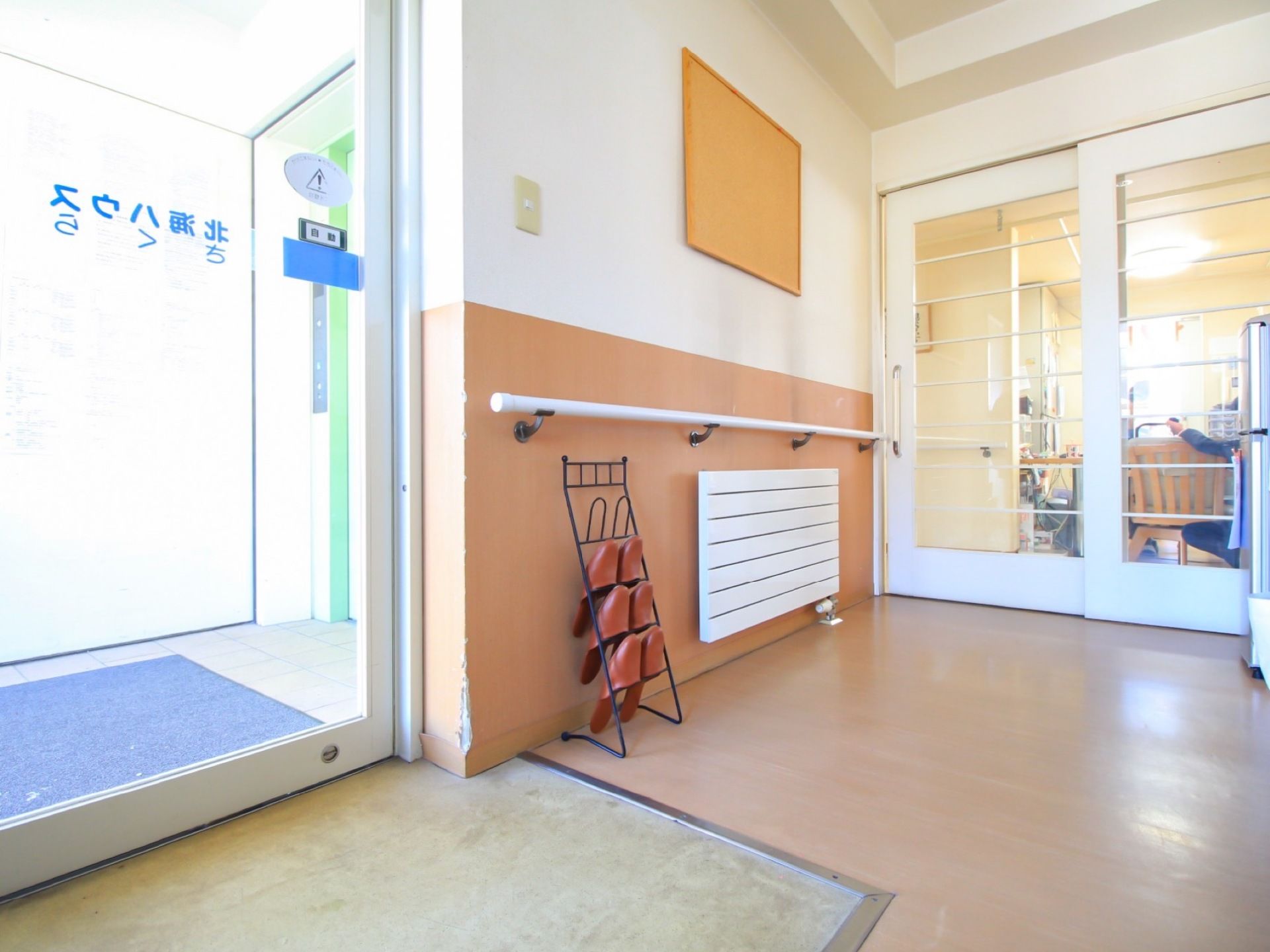 玄関入口はガラス張りの自動ドアとなっており、青い文字で施設名が書かれている。室内には、暖房が設置されている。