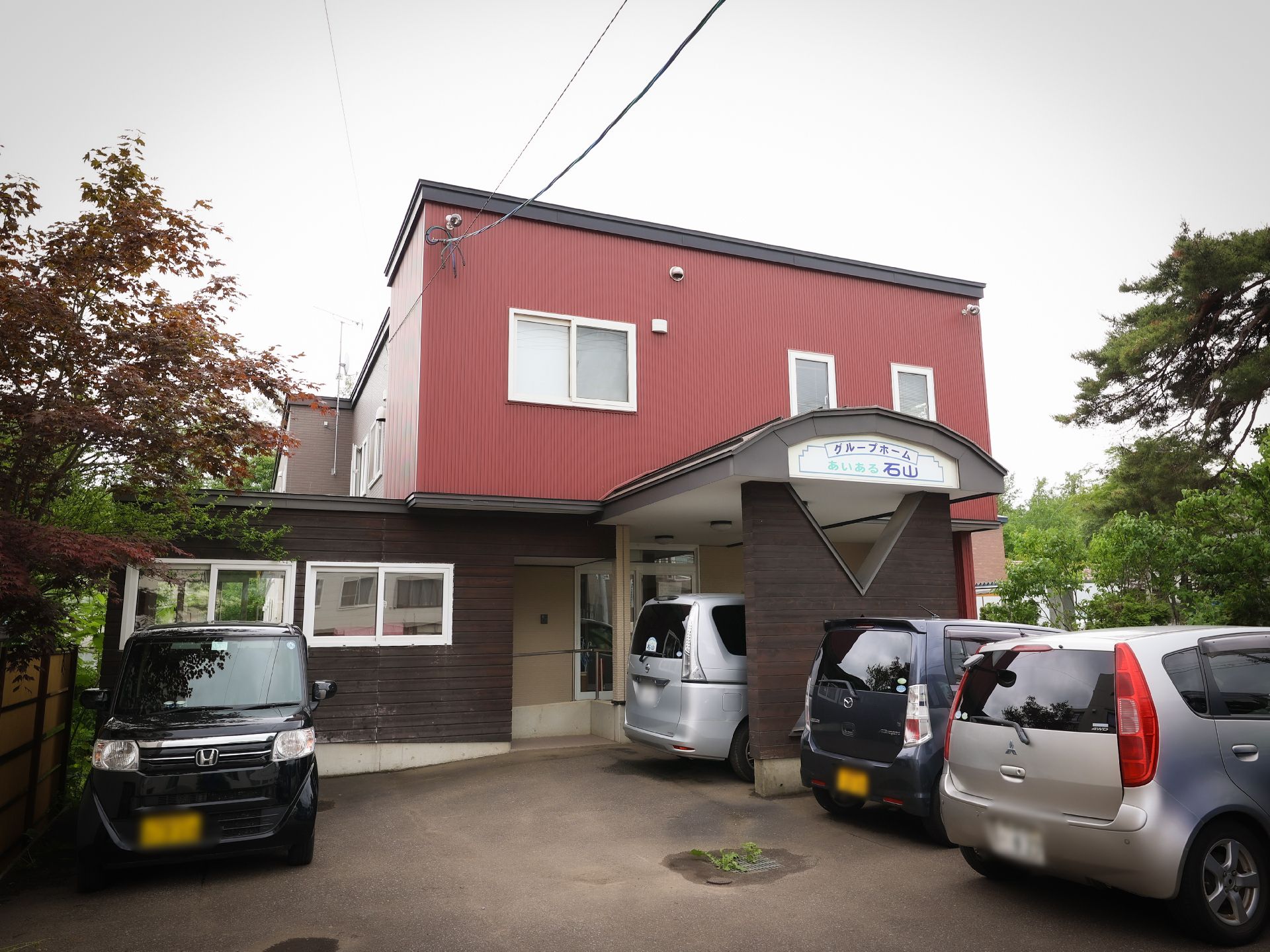 カメラに向かって笑顔を見せるスタッフと高齢者の女性。施設での何気ない一場面の様子